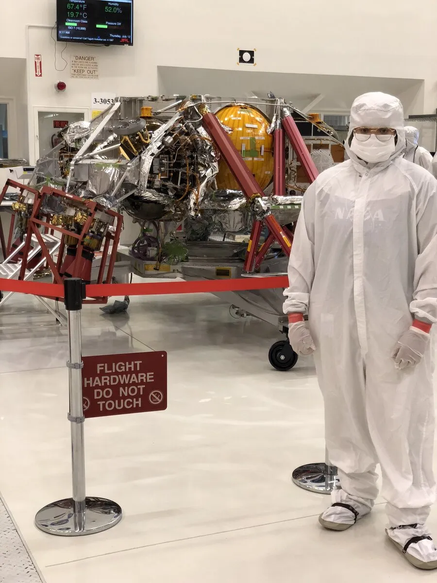 Dajae in a NASA clean room suit beside flight hardware