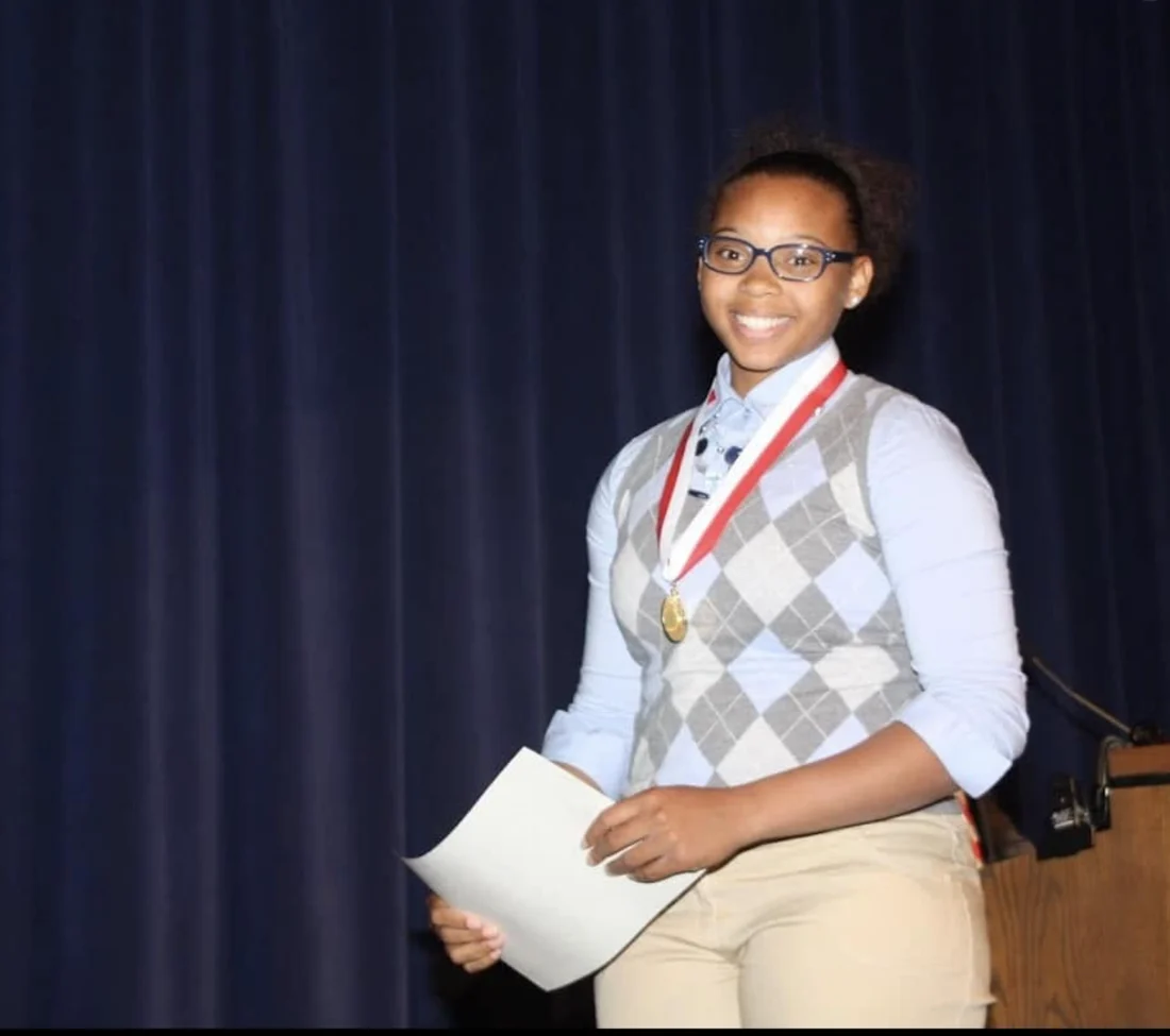 Dajae as a student holding a medal after an awards ceremony