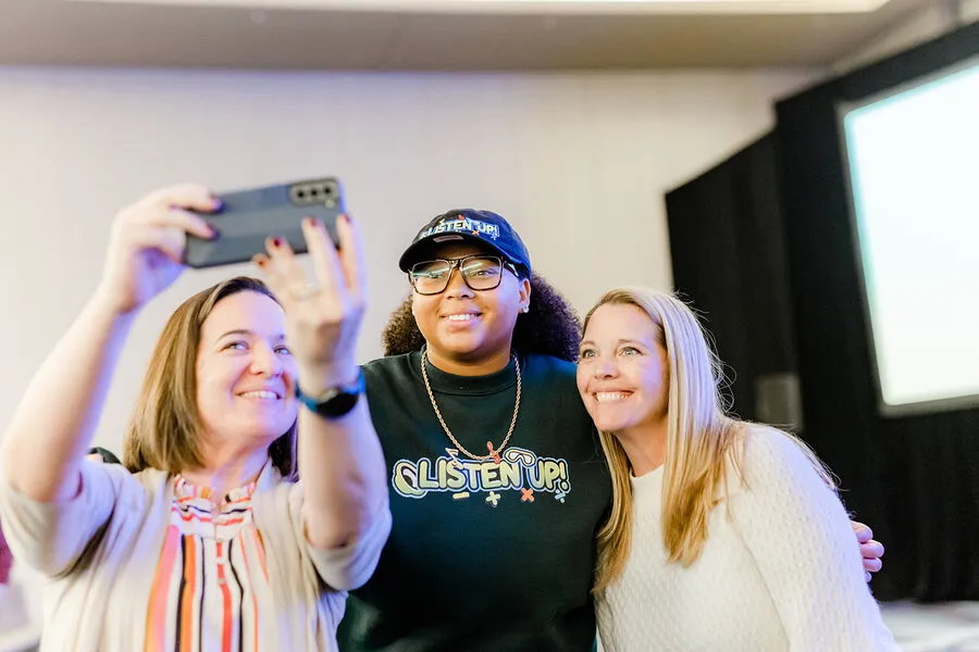 Dajae posing for a selfie with two educators